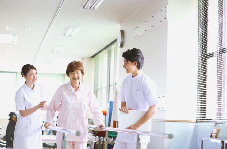 介護士と女性高齢者が笑顔で歩いている