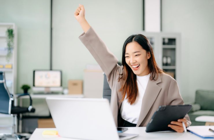 パソコンを見ながらガッツポーズする女性
