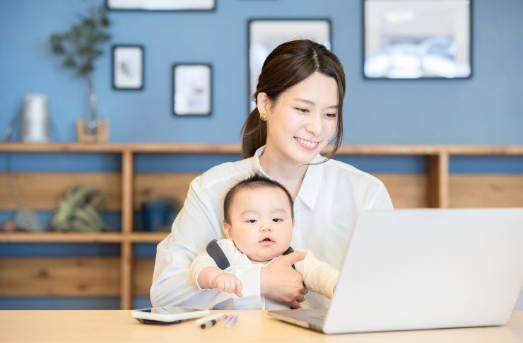 保育士の仕事内容は遊びだけじゃない!リアルな業務実態とやりがい 2 赤ちゃんを抱きノートパソコンを見る女性