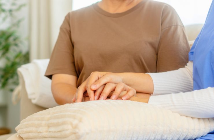 介護老人保健施設(老健)の仕事内容とは?特養との違いから給料、1日の流れまで徹底解説 2 老人の手を握る女性