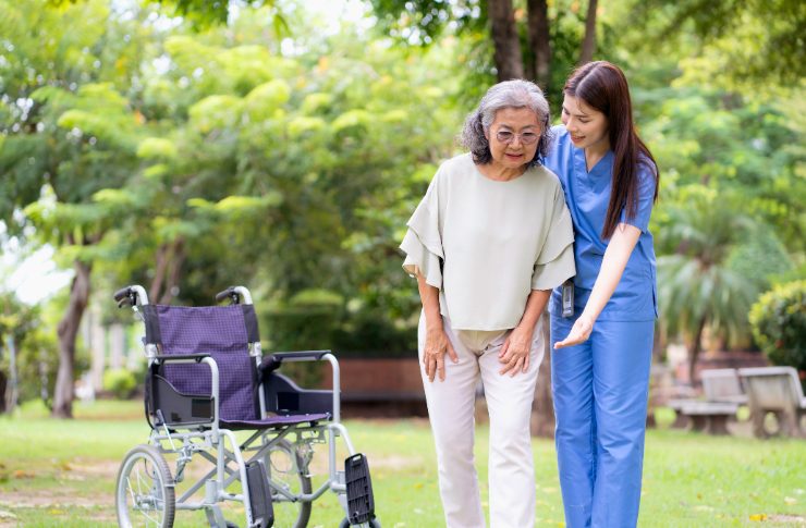 車椅子の女性のサポートを外でおこなう外国人介護職員